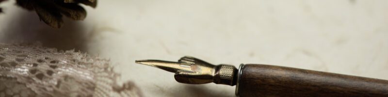 an old quill pen sitting on parchment paper